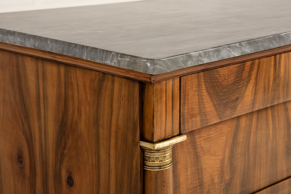 A 19th-century Italian walnut commode featuring a grey marble top, three drawer fronts with bookmatched grain, flanking column pilasters with brass mounts, and turned feet. View III
