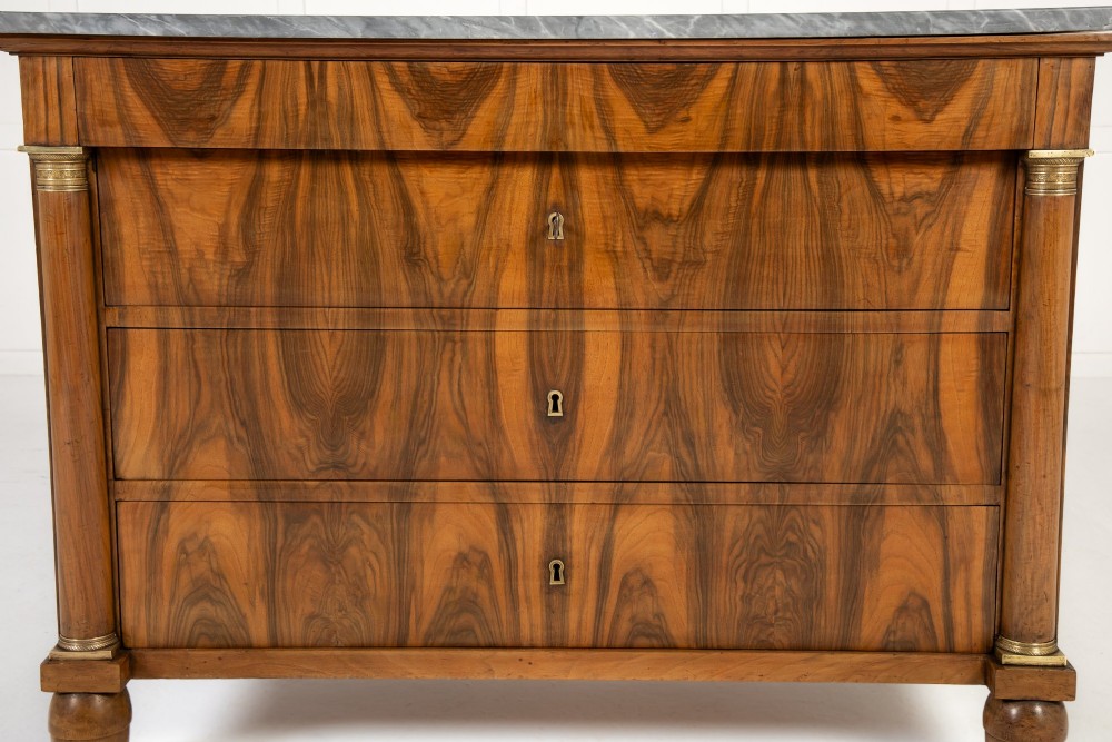 A 19th-century Italian walnut commode featuring a grey marble top, three drawer fronts with bookmatched grain, flanking column pilasters with brass mounts, and turned feet. View IV