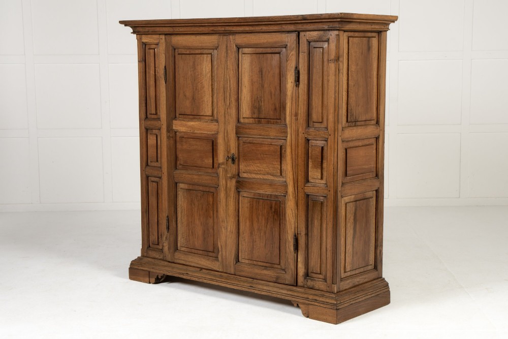 An 18th-century Italian walnut cabinet featuring twin raised geometric panel doors, moulded side panels, iron hardware, and a stepped plinth base. View II