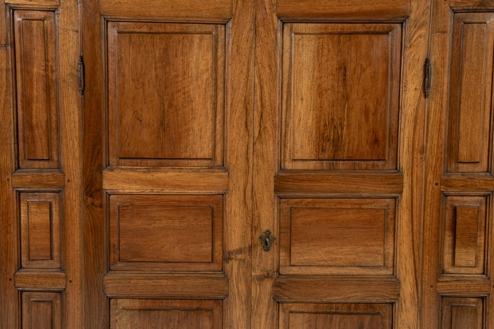 An 18th-century Italian walnut cabinet featuring twin raised geometric panel doors, moulded side panels, iron hardware, and a stepped plinth base. View III