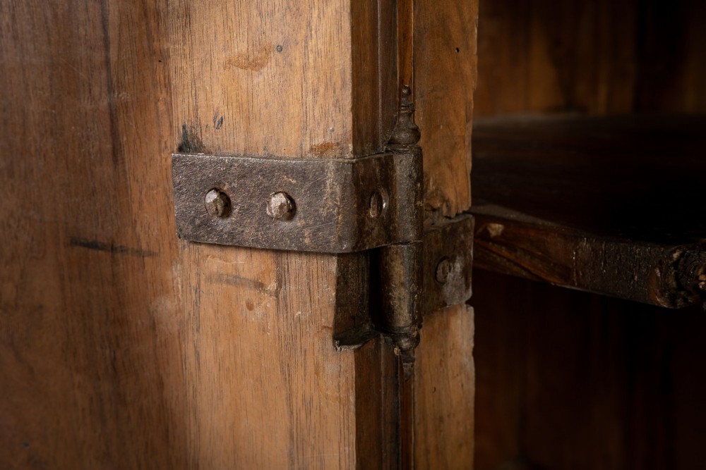 An 18th-century Italian walnut cabinet featuring twin raised geometric panel doors, moulded side panels, iron hardware, and a stepped plinth base. View VI