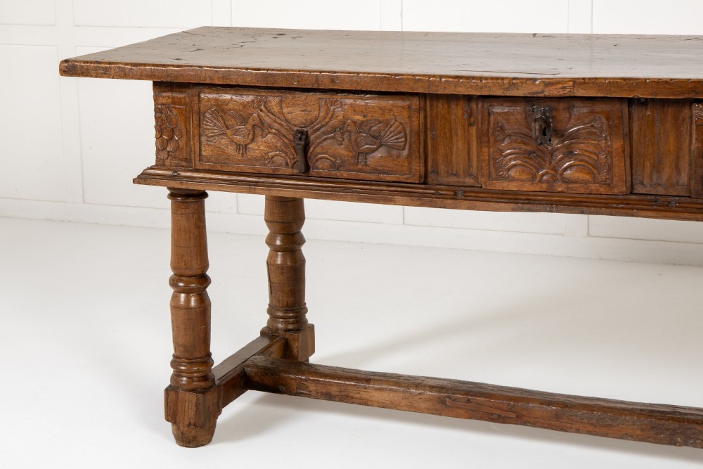 A 17th-century Spanish walnut side table featuring three carved drawer fronts, turned legs, and a low stretcher base. View II