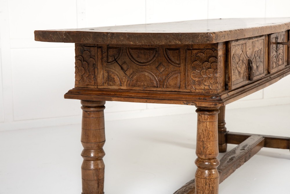 A 17th-century Spanish walnut side table featuring three carved drawer fronts, turned legs, and a low stretcher base. View VII