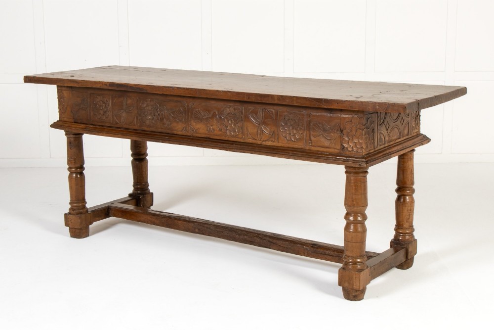 A 17th-century Spanish walnut side table featuring three carved drawer fronts, turned legs, and a low stretcher base. View XI