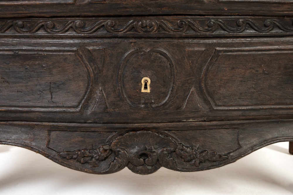 An 18th-century ebonised French bombe commode featuring three drawers, carved panels, a grey marble top, and brass keyholes. View VIII