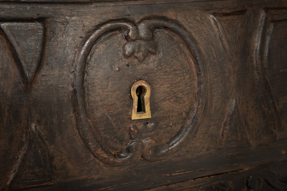 An 18th-century ebonised French bombe commode featuring three drawers, carved panels, a grey marble top, and brass keyholes. View IX