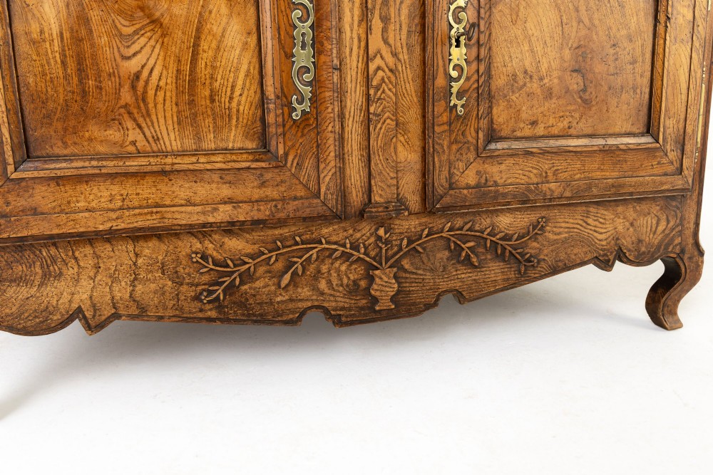 An 18th-century French ash buffet deux corps featuring two upper panelled doors, two lower doors, and carved apron details. View X