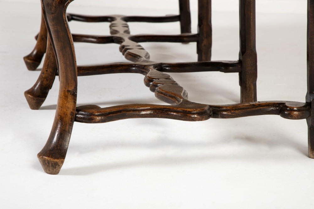 A 19th-century carved walnut settee featuring a triple chair-back design with scrollwork carving and a brown leather studded seat. View IX
