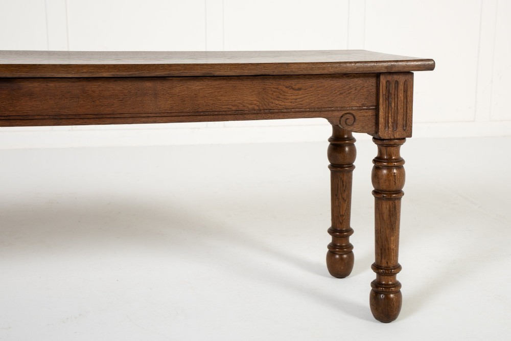 A long 19th-century dark oak bench featuring a rectangular plank seat supported by turned legs with fluted frieze details. View III