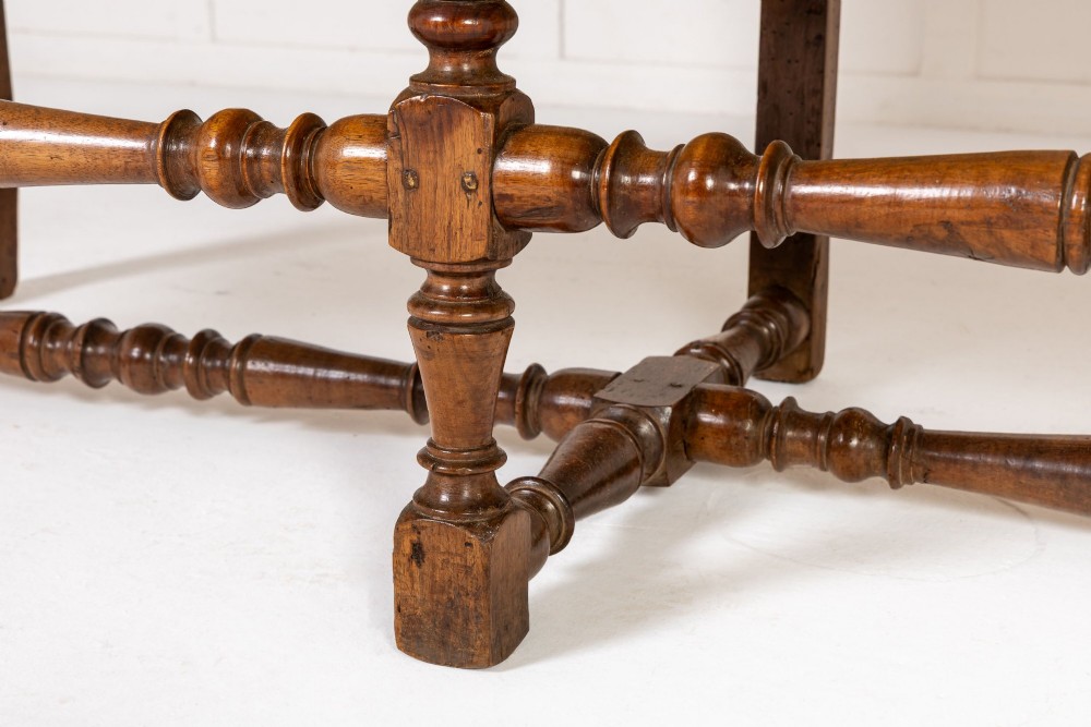An 18th-century Italian walnut settee featuring high-backed wings, flame-stitch patterned upholstery in warm ochre tones, and six turned wood legs connected by stretchers. View VII