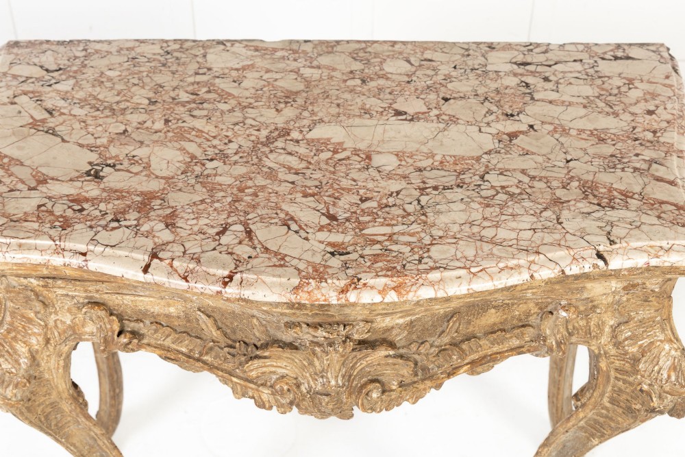 An 18th-century Italian Rococo silver-gilt console table featuring carved leaf motifs, cabriole legs, and a rectangular pink marble top. View V