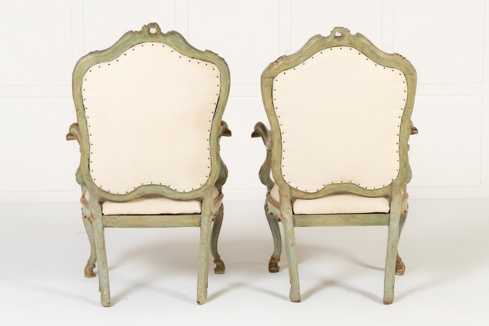 A pair of 18th-century Italian Rococo armchairs featuring pale blue painted frames with gilt detailing, carved shell aprons, curved cabriole legs, and cream upholstery. View XV