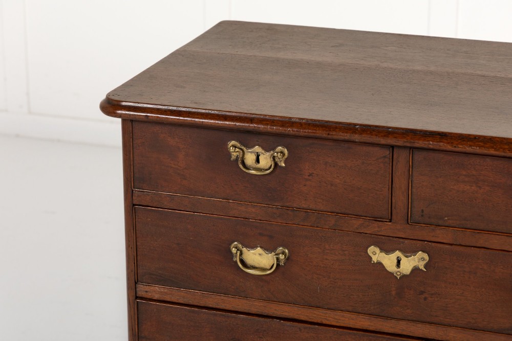 An 18th-century English walnut chest of drawers featuring two short drawers over three long drawers with brass hardware and bracket feet. View II