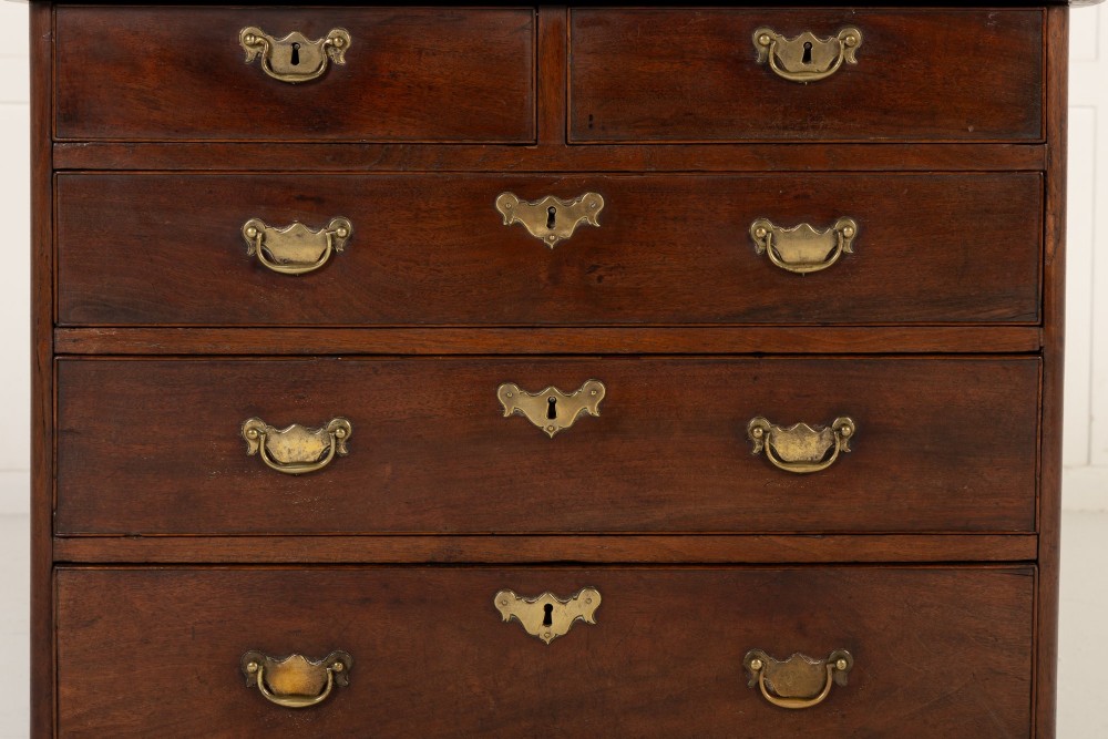 An 18th-century English walnut chest of drawers featuring two short drawers over three long drawers with brass hardware and bracket feet. View IV