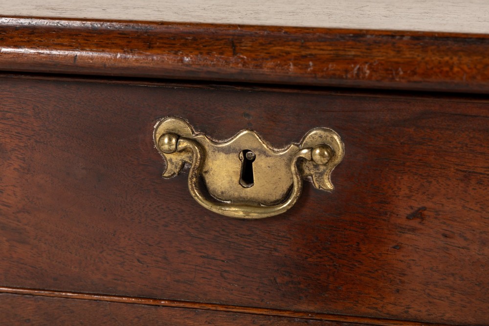 An 18th-century English walnut chest of drawers featuring two short drawers over three long drawers with brass hardware and bracket feet. View V