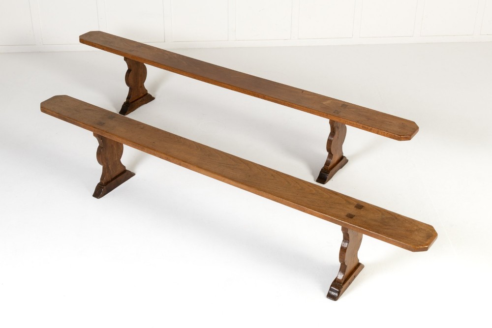 A pair of 19th-century French backless wooden hall benches featuring shaped trestle supports and visible joinery.