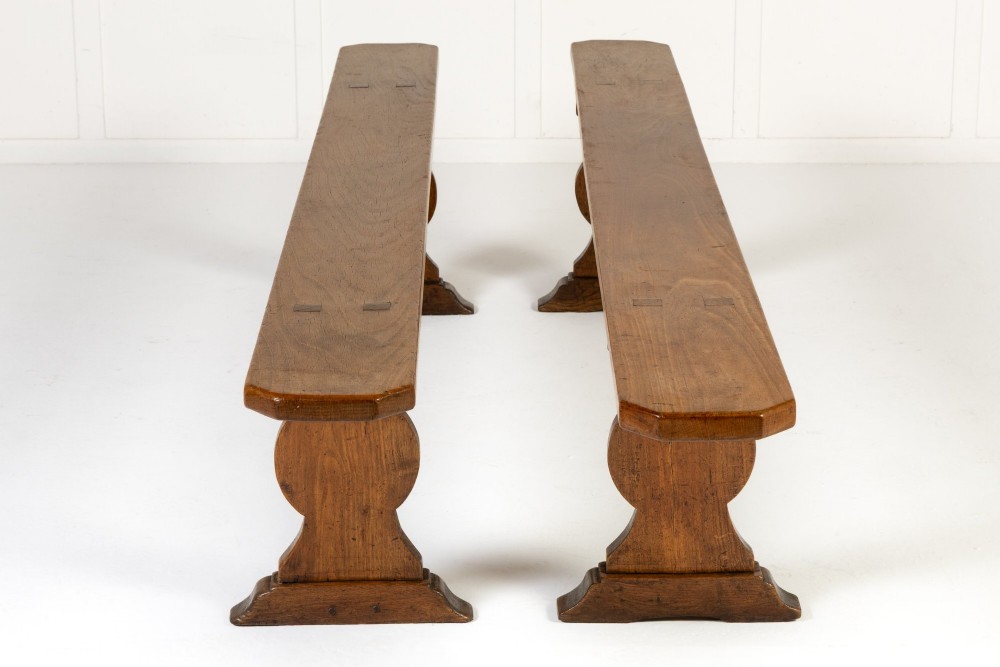 A pair of 19th-century French backless wooden hall benches featuring shaped trestle supports and visible joinery. View IV