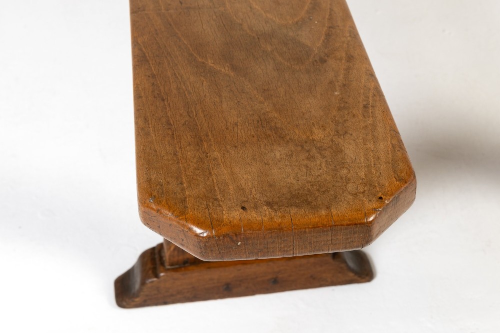 A pair of 19th-century French backless wooden hall benches featuring shaped trestle supports and visible joinery. View V