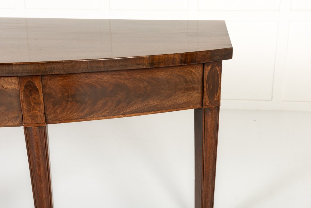 An 18th-century Georgian mahogany serving table featuring a curved apron with central oval inlay and four tapered square legs. View IV
