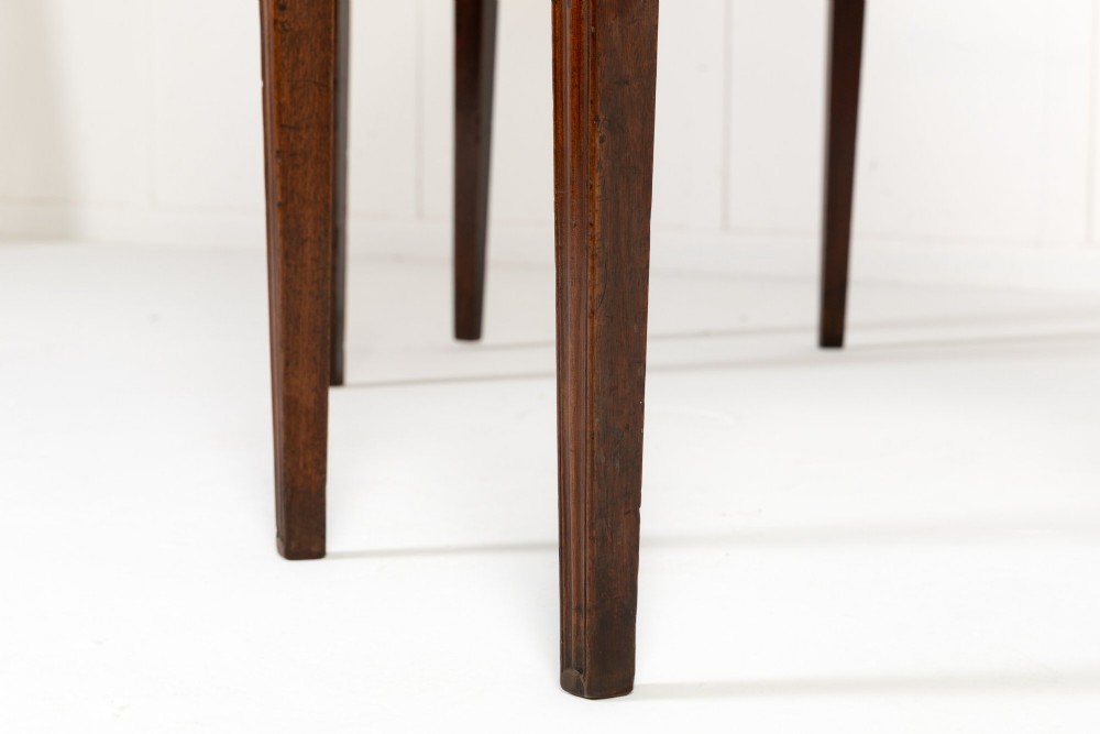 An 18th-century Georgian mahogany serving table featuring a curved apron with central oval inlay and four tapered square legs. View X