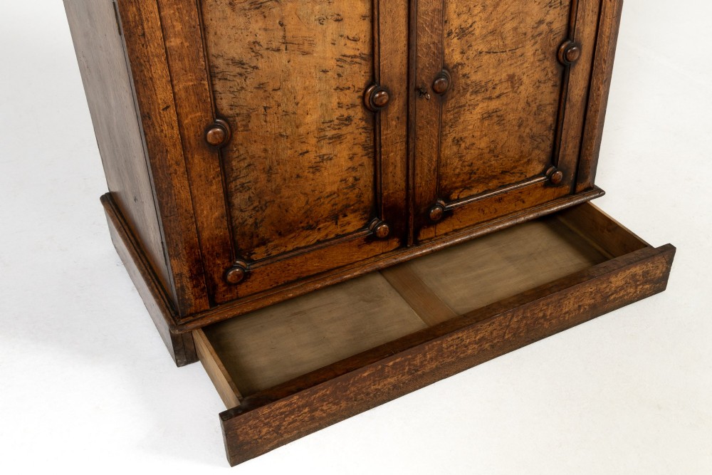 A tall 19th-century English pollard oak bookcase featuring a glazed two-door upper section and a solid panelled lower cupboard with circular boss details. View VIII