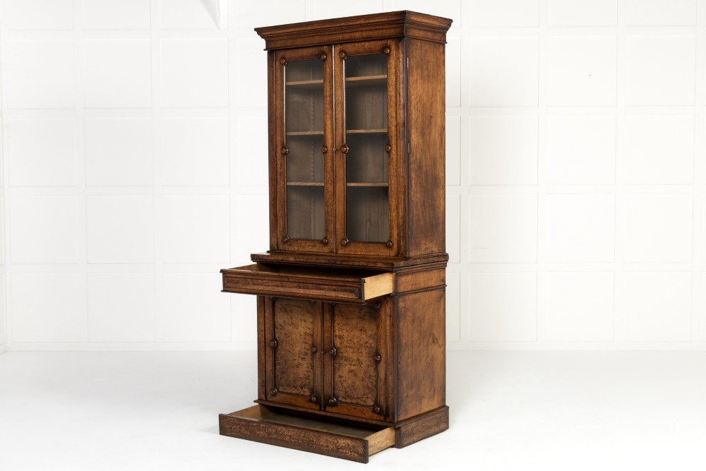 A tall 19th-century English pollard oak bookcase featuring a glazed two-door upper section and a solid panelled lower cupboard with circular boss details. View IX