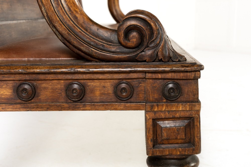 A nineteenth-century carved dark oak Gothic Revival bench featuring pointed arches on the backrest, scrolled armrests, and a fitted leather seat. View VII