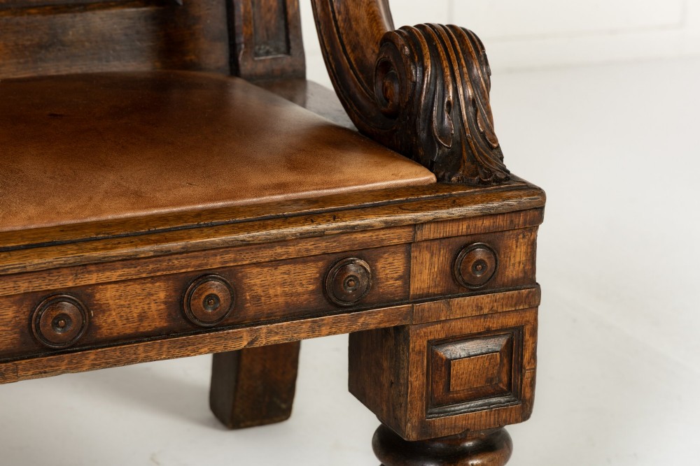 A nineteenth-century carved dark oak Gothic Revival bench featuring pointed arches on the backrest, scrolled armrests, and a fitted leather seat. View VIII