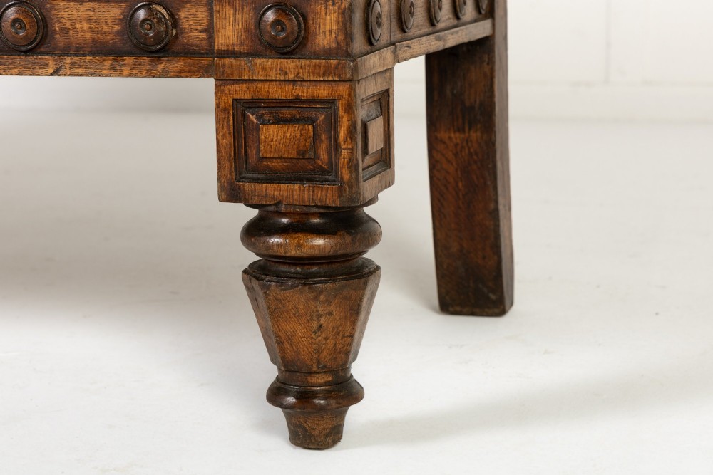 A nineteenth-century carved dark oak Gothic Revival bench featuring pointed arches on the backrest, scrolled armrests, and a fitted leather seat. View X