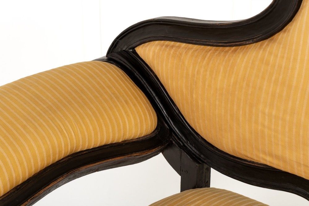 An 18th-century Italian ebonised sofa featuring a high serpentine backrest, mustard yellow striped upholstery, and carved cabriole legs. View IV