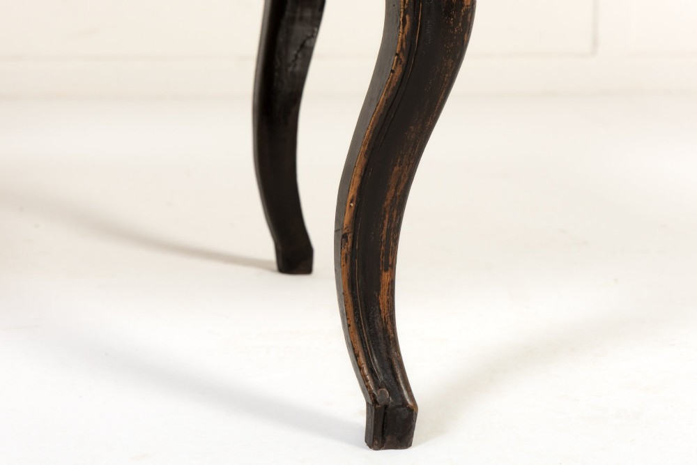 An 18th-century Italian ebonised sofa featuring a high serpentine backrest, mustard yellow striped upholstery, and carved cabriole legs. View VI