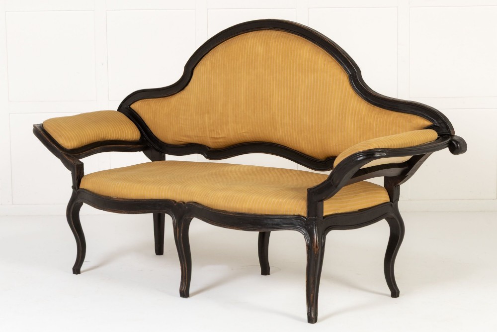 An 18th-century Italian ebonised sofa featuring a high serpentine backrest, mustard yellow striped upholstery, and carved cabriole legs. View VII