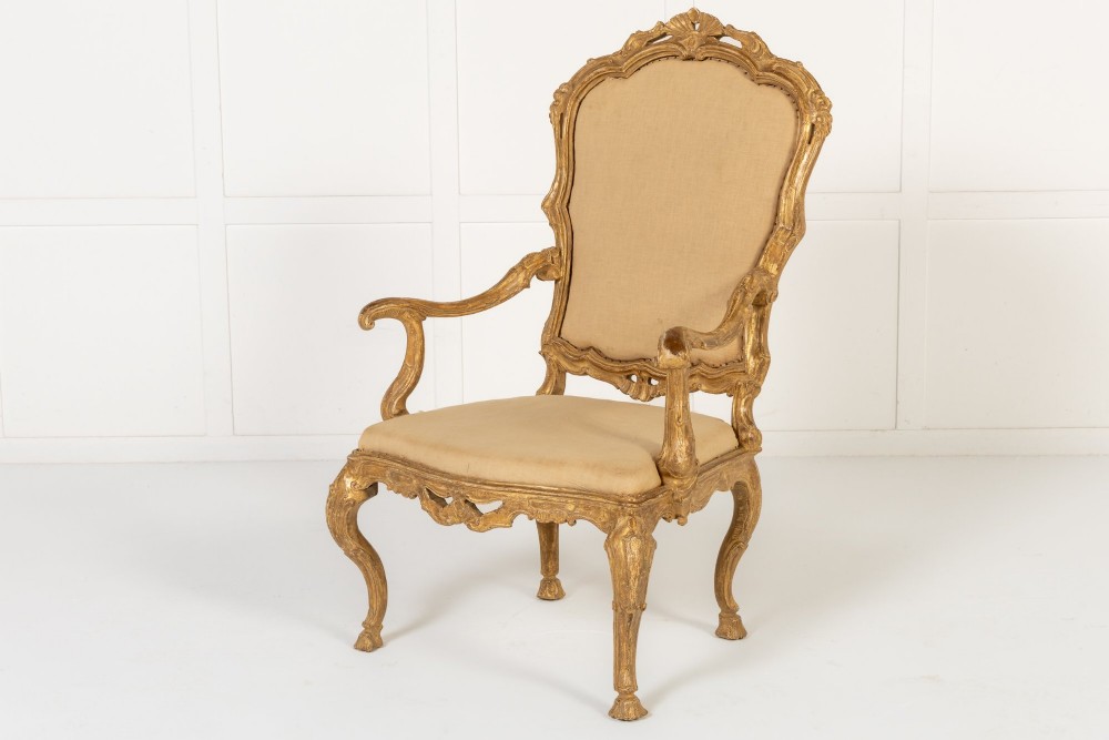 An 18th-century Italian carved giltwood armchair featuring neutral fabric upholstery, scrolled arms, and cabriole legs. View III