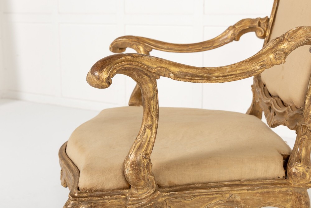 An 18th-century Italian carved giltwood armchair featuring neutral fabric upholstery, scrolled arms, and cabriole legs. View IV