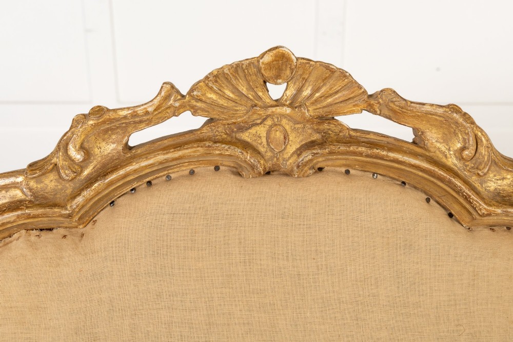 An 18th-century Italian carved giltwood armchair featuring neutral fabric upholstery, scrolled arms, and cabriole legs. View VI