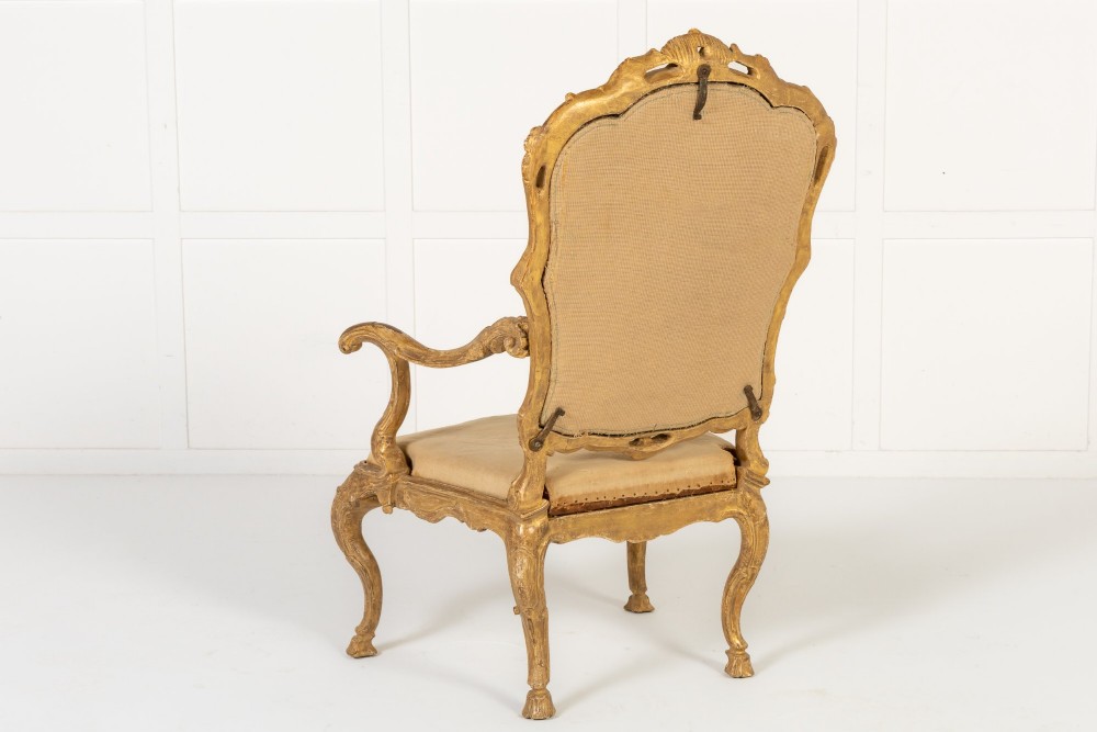 An 18th-century Italian carved giltwood armchair featuring neutral fabric upholstery, scrolled arms, and cabriole legs. View VIII
