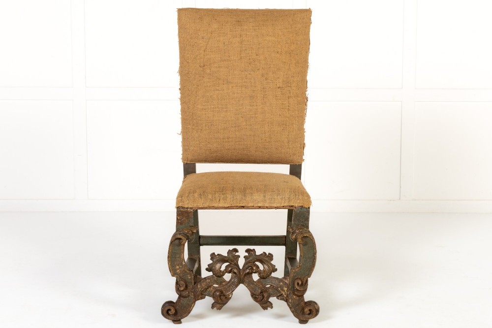 A pair of 17th-century Italian side chairs featuring tall backs upholstered in natural brown hessian, resting on elaborately carved scrollwork legs with a green painted finish. View II