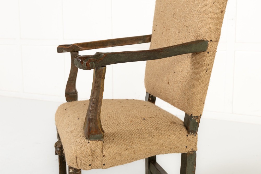 A high-backed 17th-century Italian Baroque armchair upholstered in beige hessian fabric with intricately carved wooden arms, legs, and a carved scroll front stretcher. View III