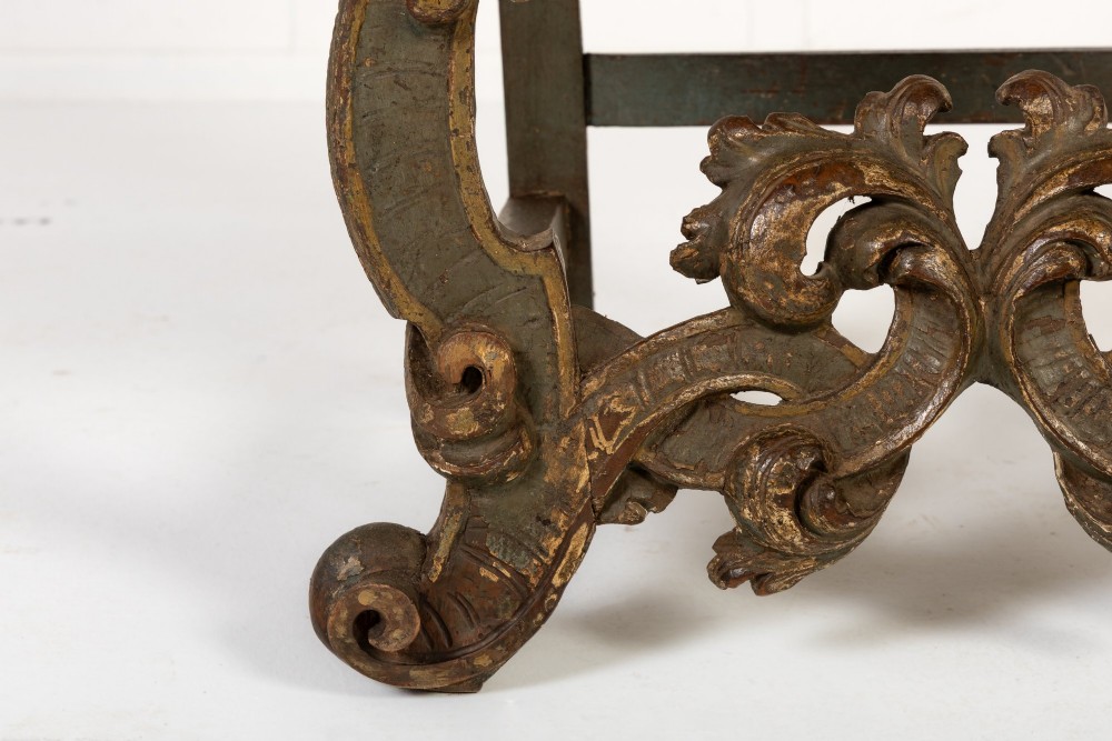 A high-backed 17th-century Italian Baroque armchair upholstered in beige hessian fabric with intricately carved wooden arms, legs, and a carved scroll front stretcher. View VI