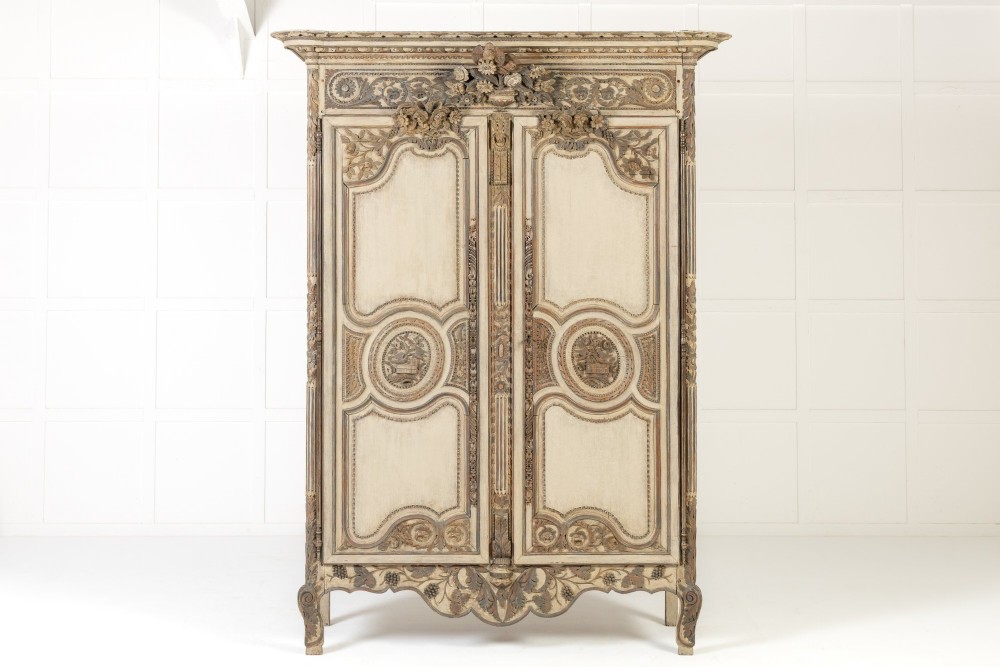 An eighteenth-century carved French painted oak armoire featuring two doors with ornate floral mouldings and short cabriole feet.