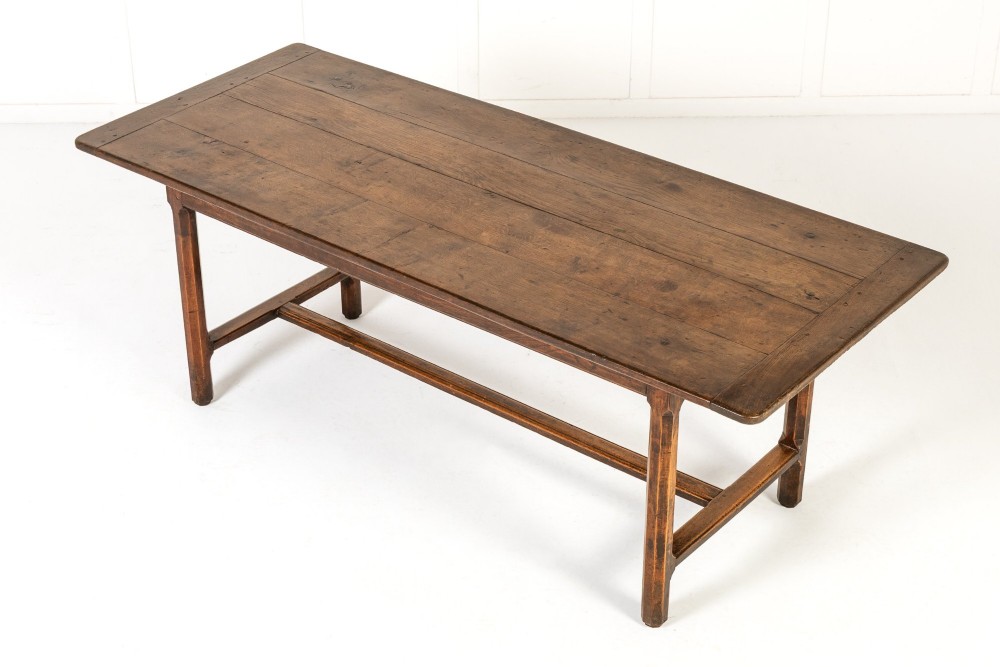 An 18th-century George III oak farmhouse dining table with a rectangular plank top and straight legs joined by low stretchers.