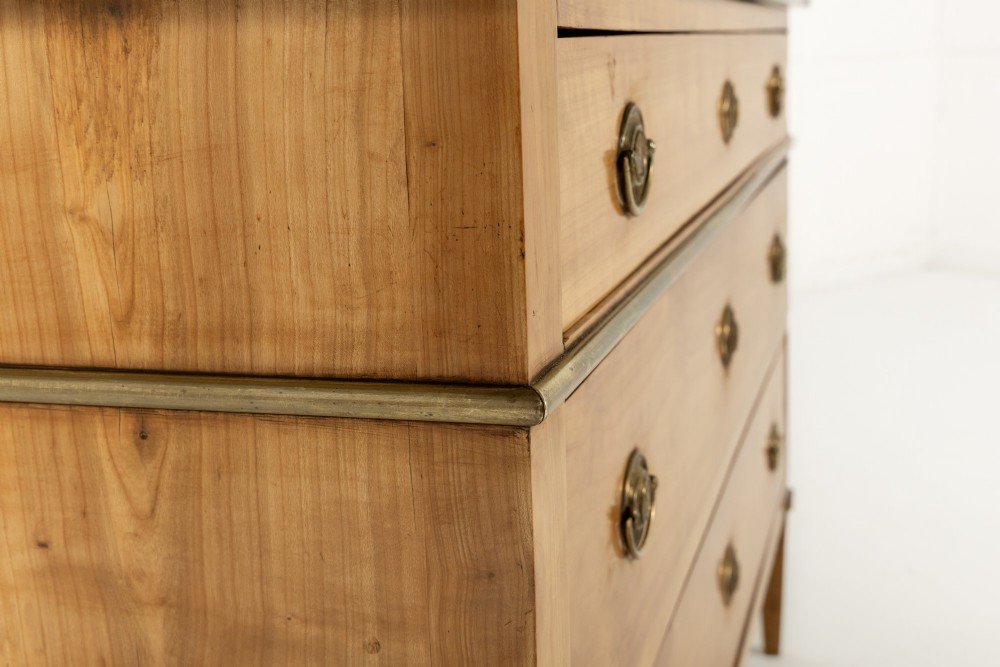 An 18th-century French cherrywood commode featuring three drawers with round brass ring pull handles, an oval keyhole escutcheon, tapered legs, and a grey marble top. View VII