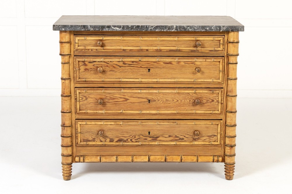 A 19th-century French pine chest of drawers featuring carved faux bamboo borders, four drawers with turned handles, and a grey marble top.