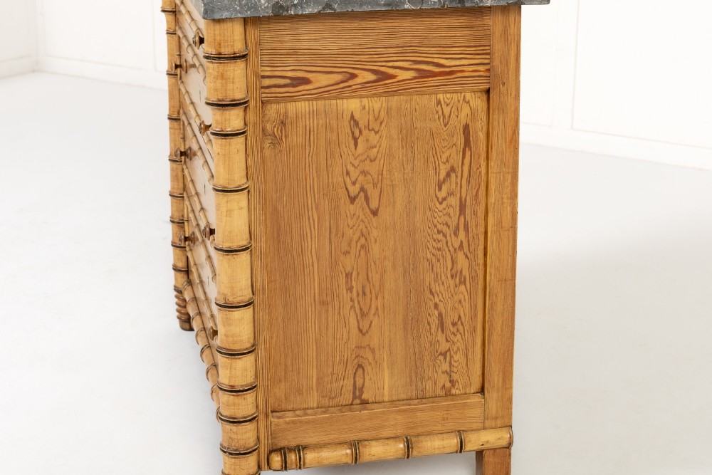 A 19th-century French pine chest of drawers featuring carved faux bamboo borders, four drawers with turned handles, and a grey marble top. View V