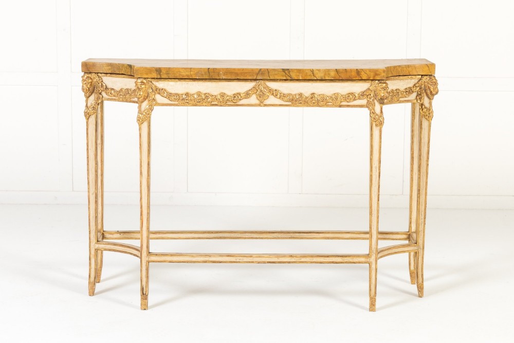 A 19th-century Italian Neoclassical console table featuring a painted cream frame, carved parcel gilt floral swags, tapered legs, and a marble top.