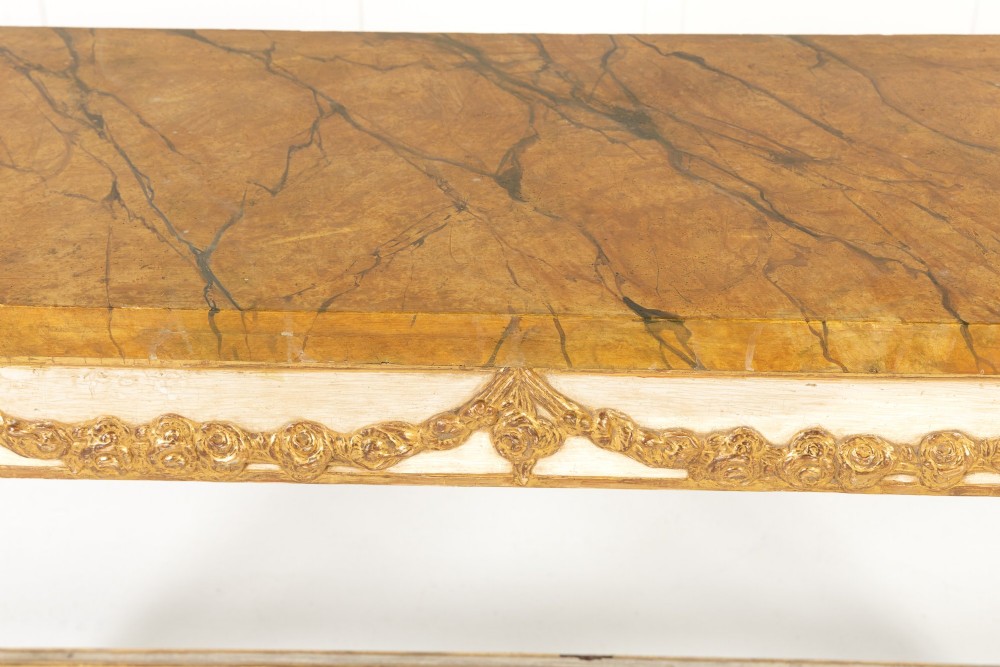 A 19th-century Italian Neoclassical console table featuring a painted cream frame, carved parcel gilt floral swags, tapered legs, and a marble top. View V