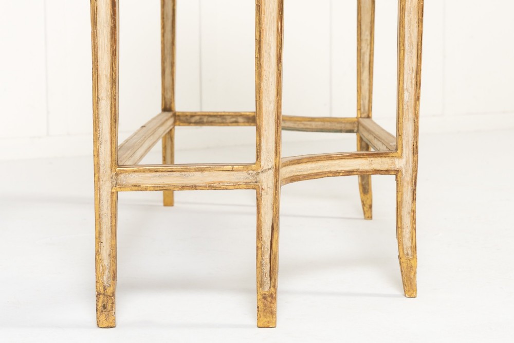 A 19th-century Italian Neoclassical console table featuring a painted cream frame, carved parcel gilt floral swags, tapered legs, and a marble top. View X
