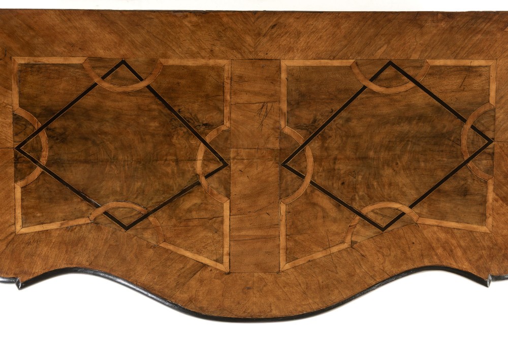 An 18th-century German walnut commode featuring three serpentine drawers with dark wood strapwork inlay and ornate brass escutcheons. View VIII
