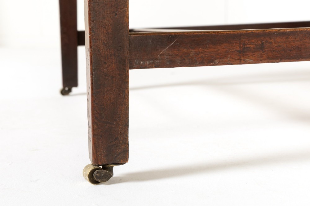 An 18th-century mahogany wingback armchair upholstered in neutral beige fabric with square timber legs and brass castors. View V