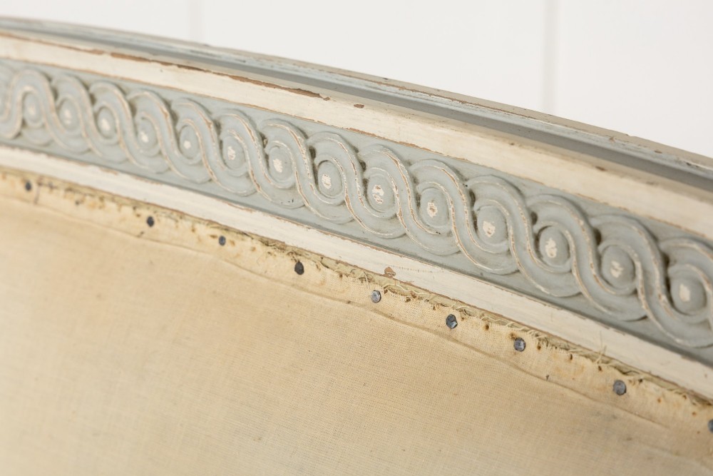 A 19th-century French Neoclassical double bed frame with a light grey painted finish, fluted posts topped with finials, and an arched cream upholstered headboard. View III